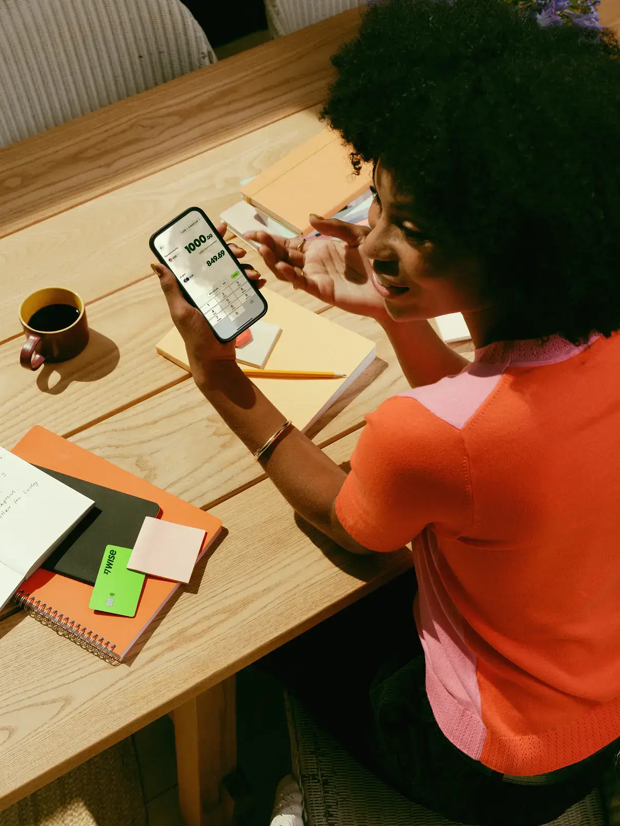 Uma mulher usando o aplicativo da Wise no telefone, vendo as moedas e as taxas de câmbio